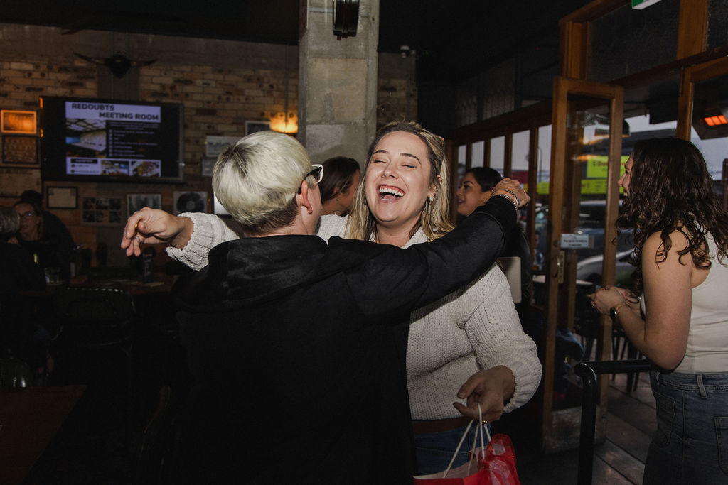 Two women sharing a warm hug and laughing at the Morrinsville pop up