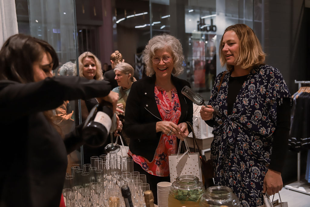 Guests laughing over drinks at the fashion event