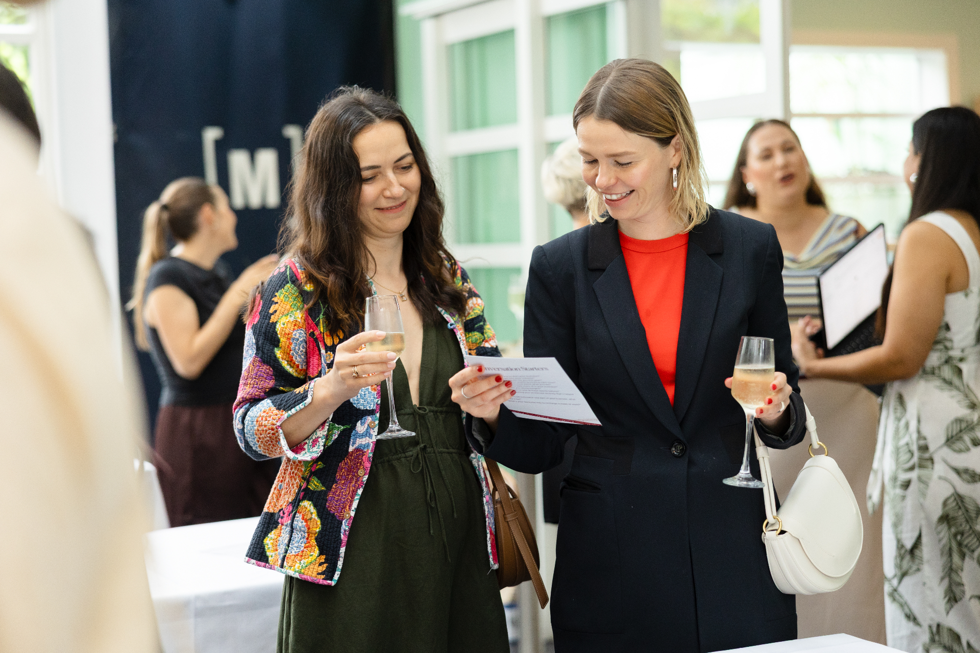 Two guests reading conversation starter cards over a glass of bubbles
