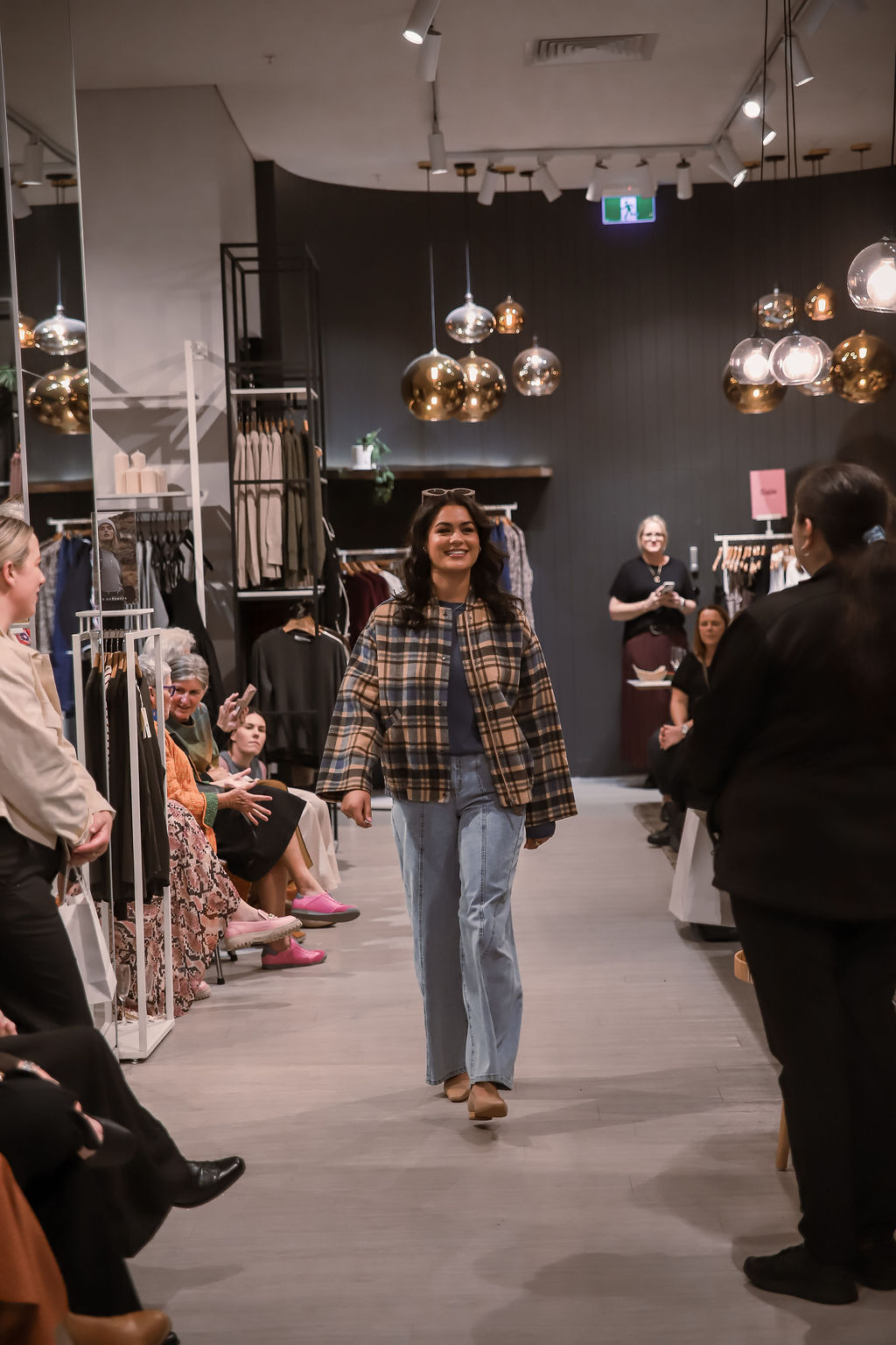 A model walking the runway in a check jacket and jeans