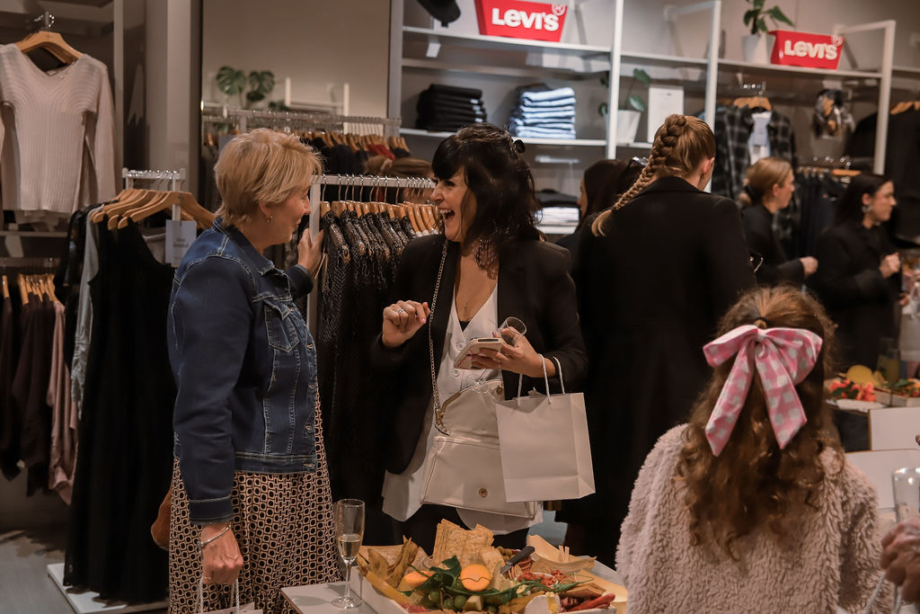 Guests chatting among the racks with goodie bags in hand