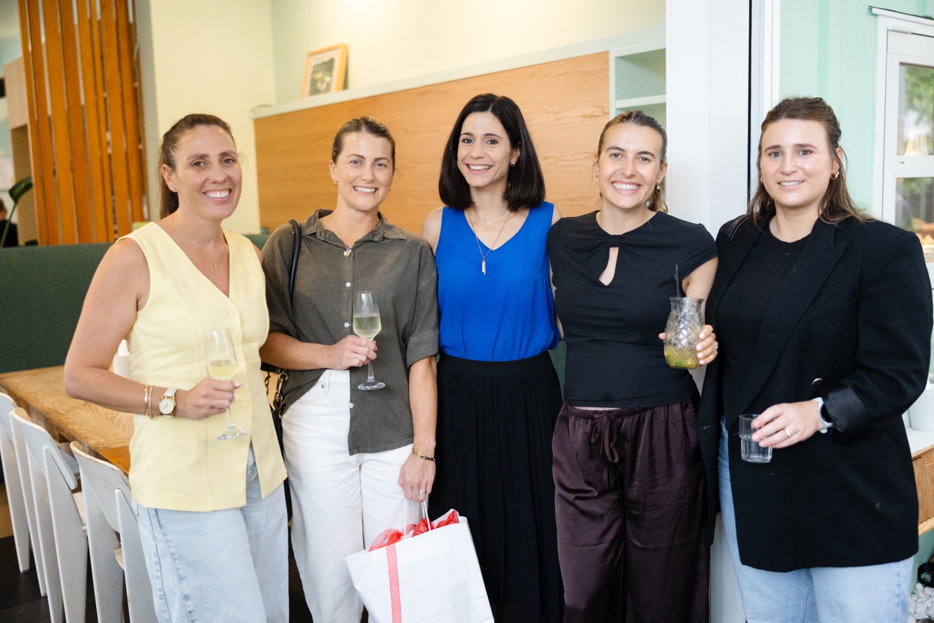 Five guests smiling together beside the long table