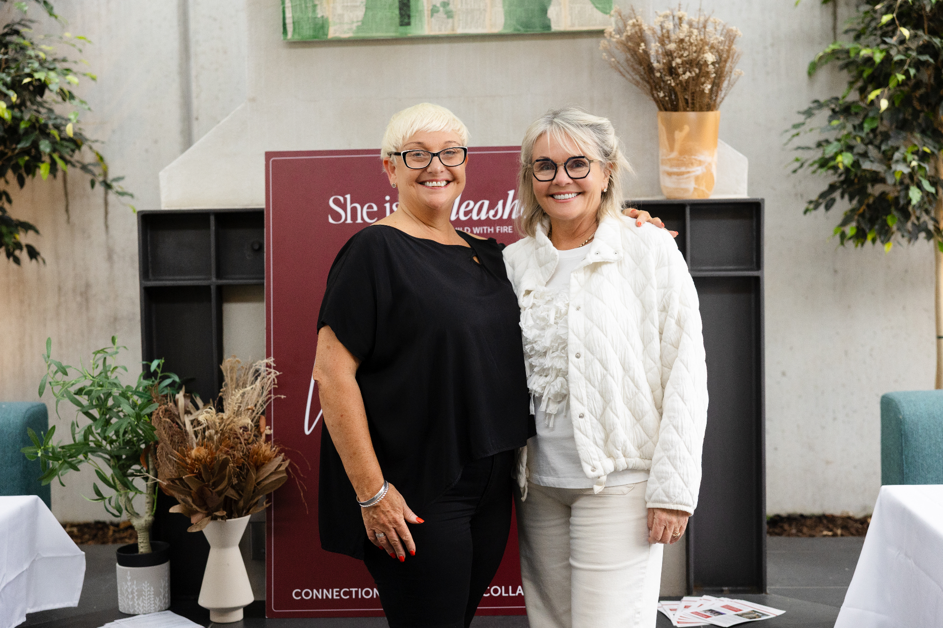 Two guests in front of the She Is Unleashed backdrop