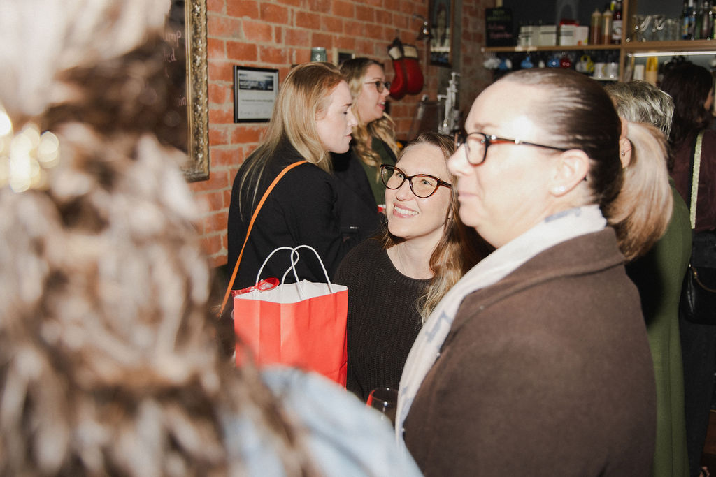 Women deep in conversation against the brick wall at The Redoubt
